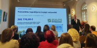 Attēlā redzami cilvēki un liels ekrāns