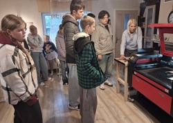 bērni ekskursijā pie lāzergravētāja iekārtas 