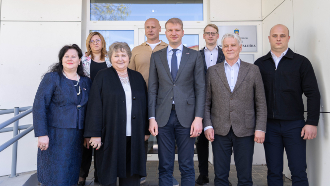 Attēlā redzams klimata un enerģētikas ministrs Kaspars Melnis, Balvu novada vadība un deputāti. Visi nostājušies uz kopīgu foto pie Balvu novada pašvaldības ēkas.