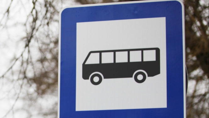 Ceļa zīme "Autobusa un trolejbusa pietura" tuvplānā. Uz zīmes zilā rāmja un baltā fona attēlots melns autobusa simbols.