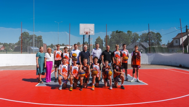 Basketbola komandas un oficiālo pārstāvju kopbilde uz 3×3 basketbola laukuma.