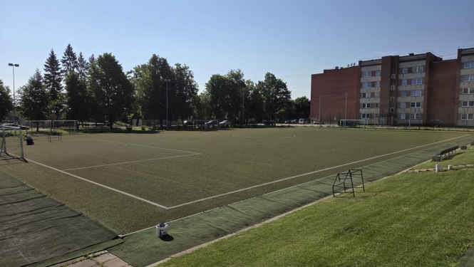 Skats uz Balvu Valsts ģimnāzijas futbola laukumu ar mākslīgo segumu saulainā dienā.