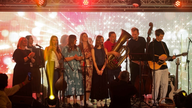 Attēlā redzama muzikantu grupa uz skatuves.