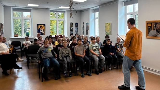 Attēlā redzami bērnu grupa, tikšanās ar rakstnieku