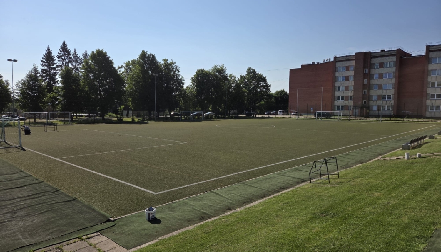 Skats uz Balvu Valsts ģimnāzijas futbola laukumu ar mākslīgo segumu saulainā dienā.