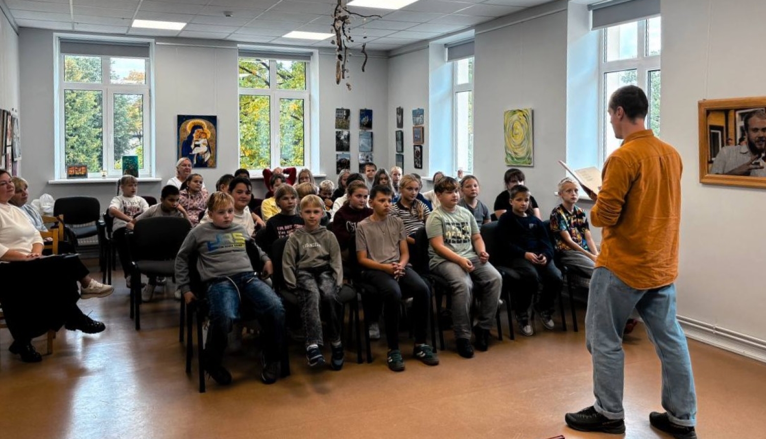 Attēlā redzami bērnu grupa, tikšanās ar rakstnieku