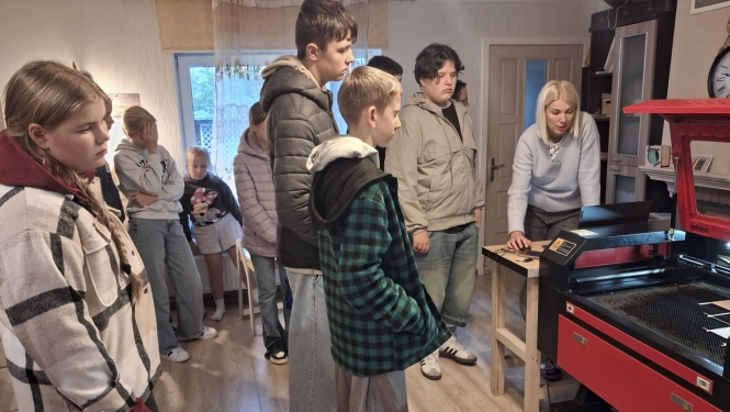 bērni ekskursijā pie lāzergravētāja iekārtas 