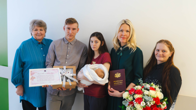 Balvu novada 2026. gada pirmais bērniņš meitenīte Mia kopā ar vecākiem un pārstāvjiem no Balvu novada pašvaldības