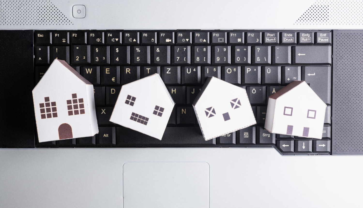 Uz datora kvaliatūras izkārtotas četras papīra mājiņas