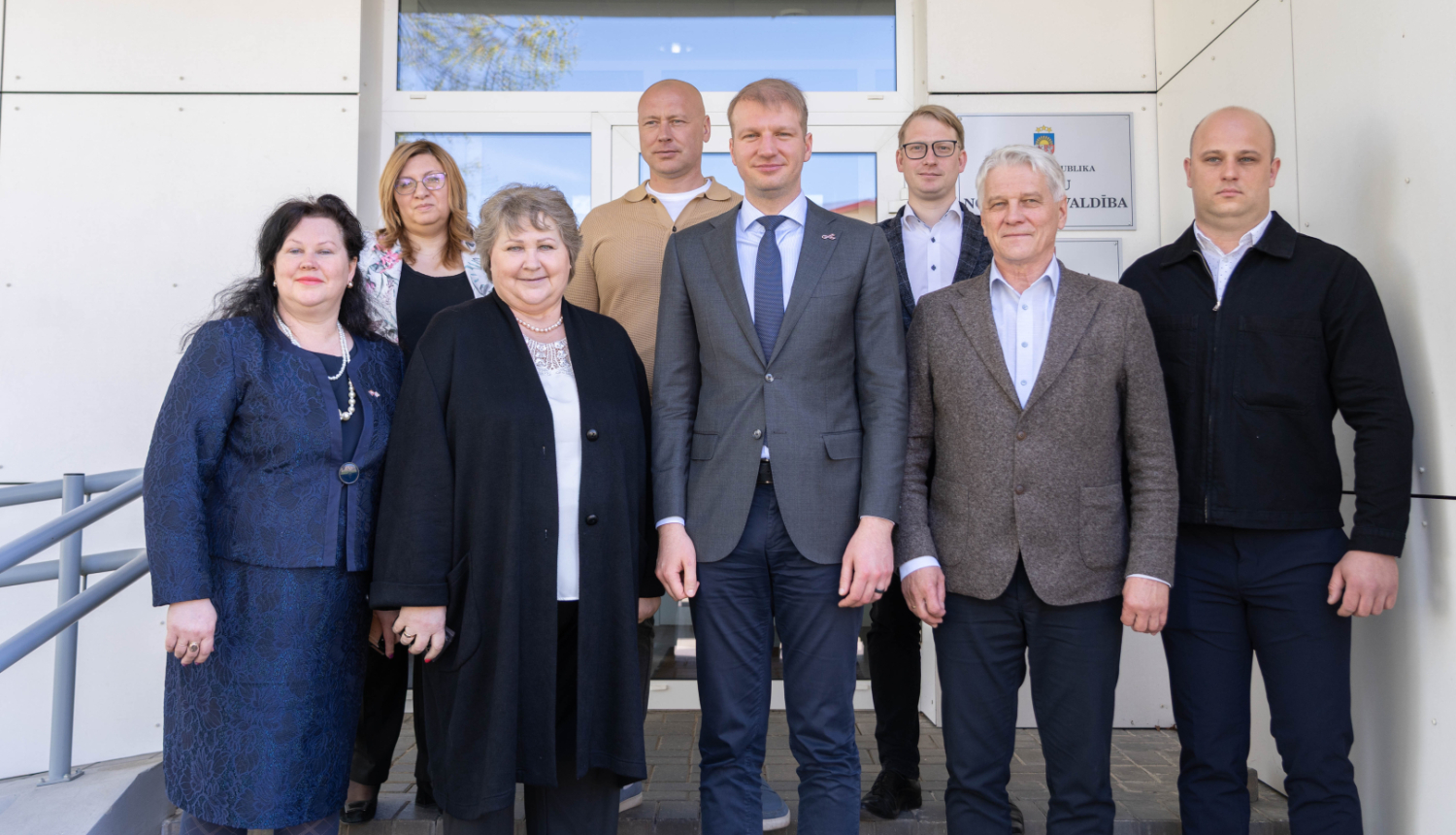 Attēlā redzams klimata un enerģētikas ministrs Kaspars Melnis, Balvu novada vadība un deputāti. Visi nostājušies uz kopīgu foto pie Balvu novada pašvaldības ēkas.