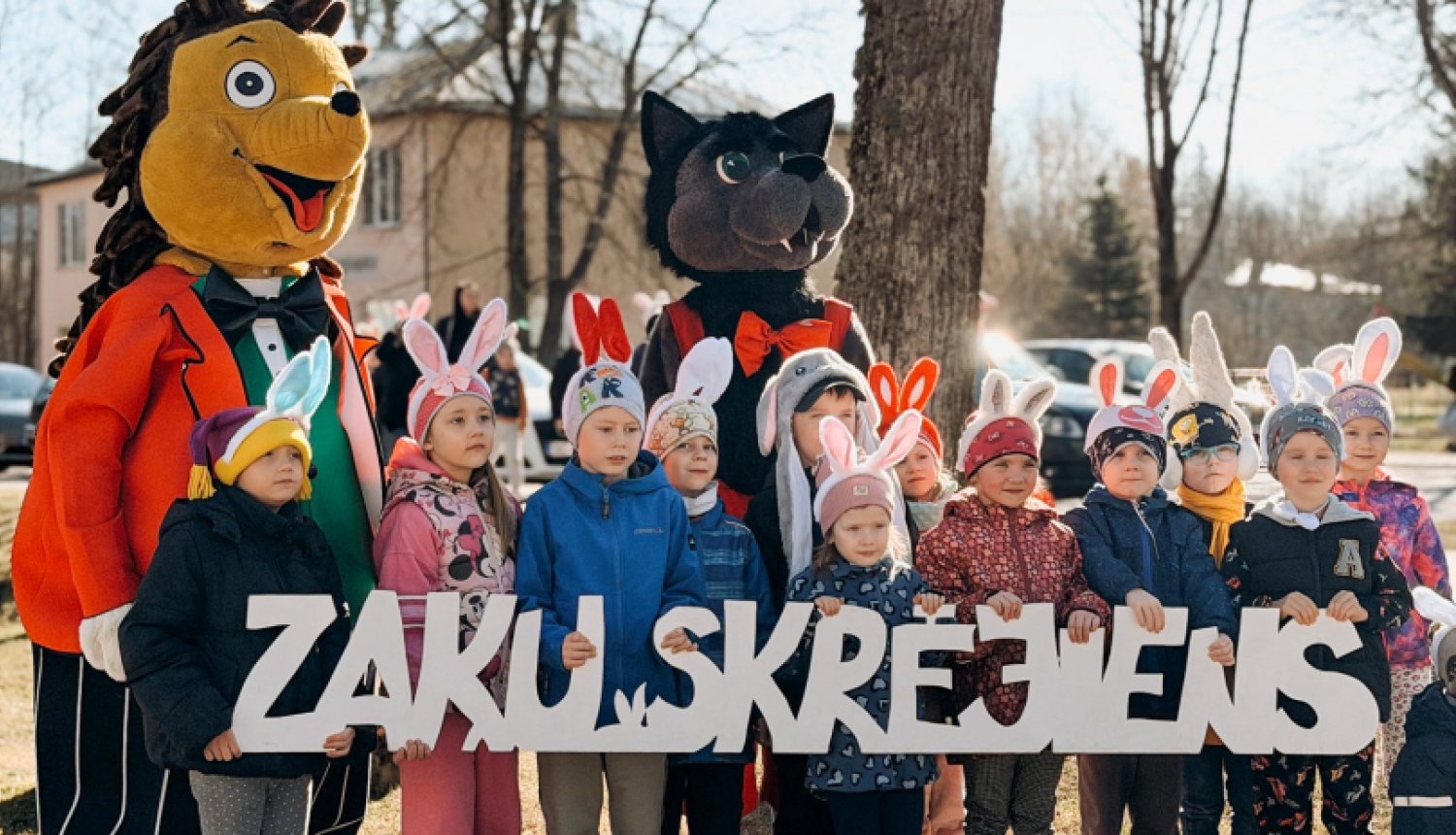Pirmskolas vecuma bērni ar zaķa ausīm tur rokās nosaukumu ''Zaķu skrējiens''
